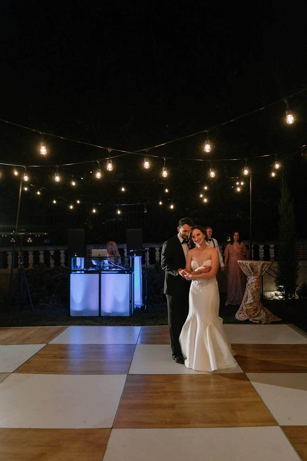 A wedding couple dancing under string lights